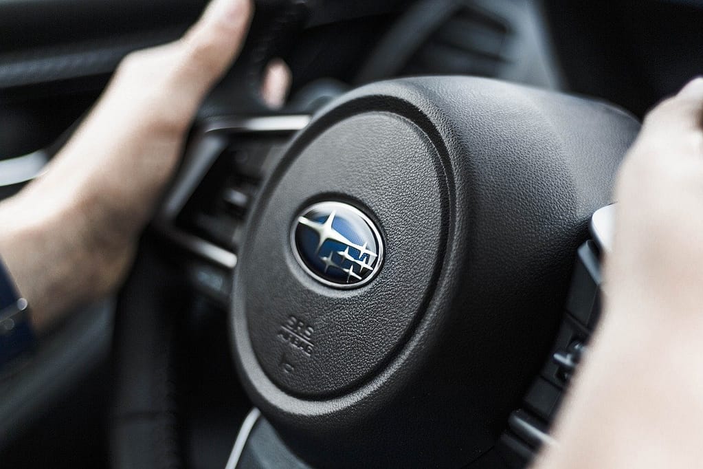 A closeup view of a Subaru steering wheel that features the brand's recognizable logo and contemporary design elements.